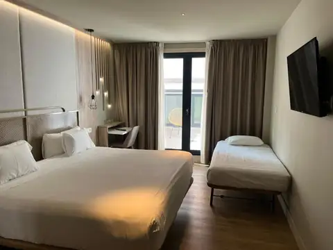 Habitación con cama de matrimonio, cama supletoria y televisor en el IMI Hotel & Spa