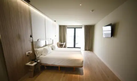 Habitación amplia con dos camas juntas, suelo de madera y ventanal en el IMI Hotel & Spa