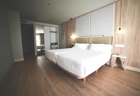 Habitación con dos camas, cabecero tapizado y lámparas colgantes en el IMI Hotel & Spa
