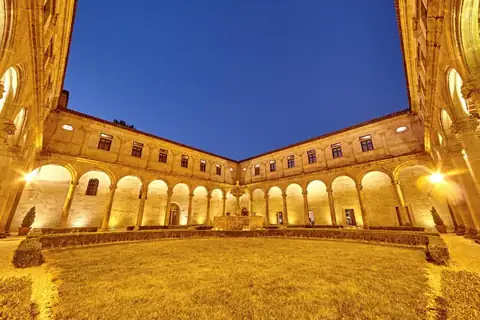 Claustro renacentista iluminado de noche con fuente central en el Monasterio de San Clodio