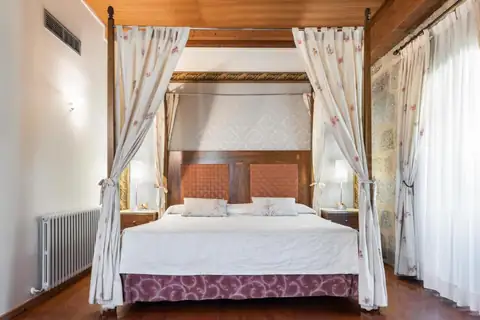 Habitación con cama con dosel y muro de piedra en el Monasterio de San Clodio