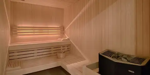 Sauna de madera con bancos y estufa en el NH Collection A Coruña Finisterre