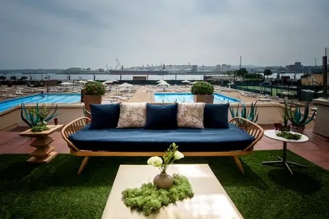 Terraza con sofá y vistas a las piscinas y al puerto del NH Collection A Coruña Finisterre