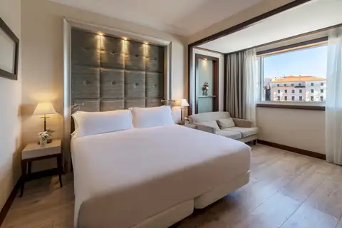 Habitación con cama doble, sofá y ventana a la ciudad del NH Collection A Coruña Finisterre