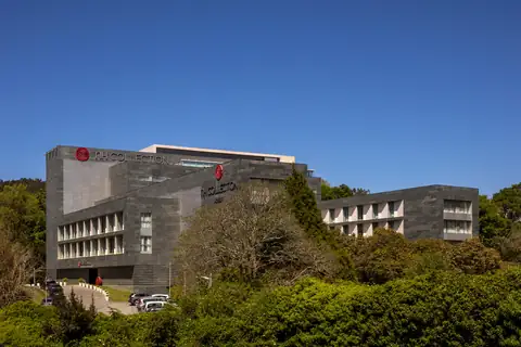Edificio del NH Collection Santiago de Compostela entre árboles bajo el cielo azul