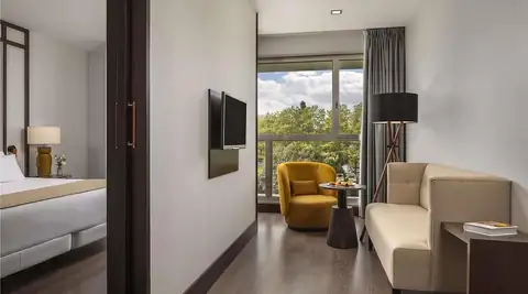 Junior suite con salón, sofá y butaca amarilla en el NH Collection Santiago