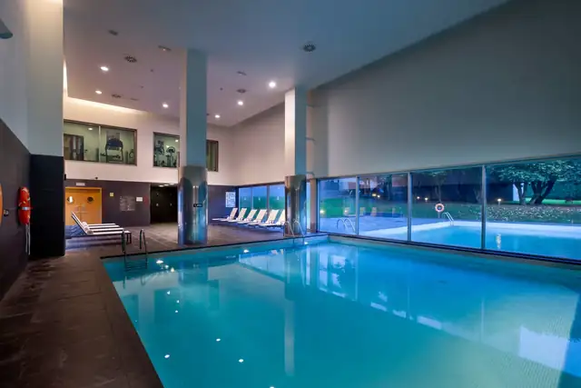Piscina interior climatizada con ventanales al jardín en el NH Collection Santiago de Compostela