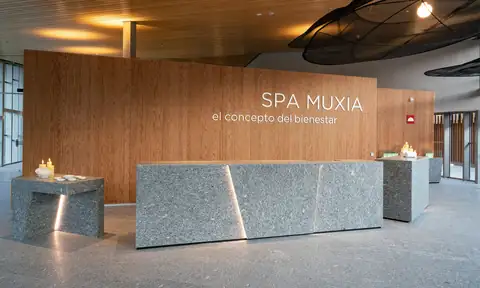 Recepción del Spa Muxía con mostrador de piedra y pared de madera en el Parador Costa da Morte