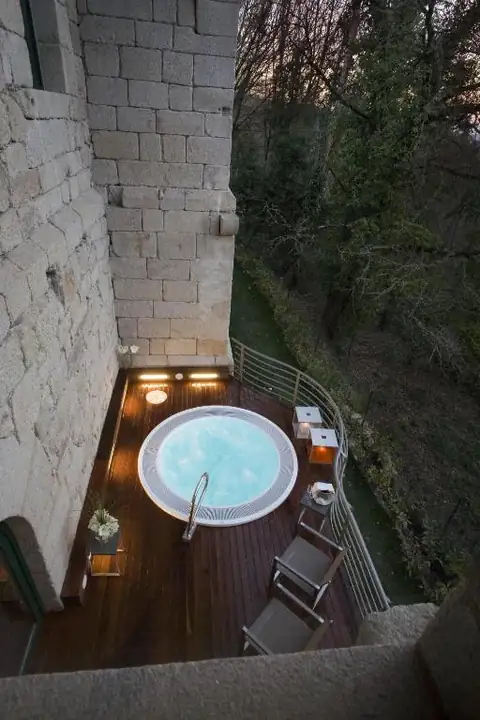 Terraza con jacuzzi exterior sobre el bosque al anochecer en el Parador de Santo Estevo
