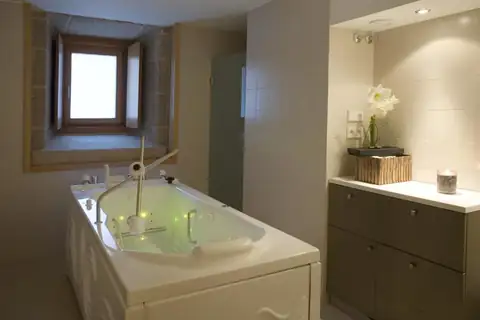 Cabina con bañera de hidromasaje y ventana en el muro de piedra del Parador de Santo Estevo