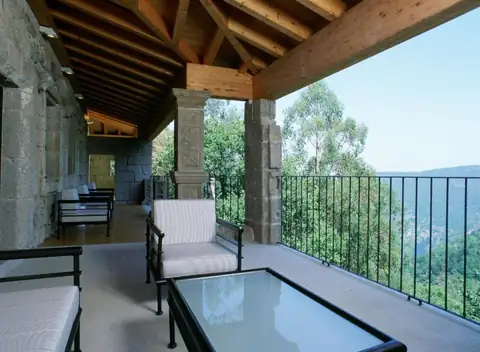Galería cubierta con sillones y vistas al cañón y los bosques desde el Parador de Santo Estevo