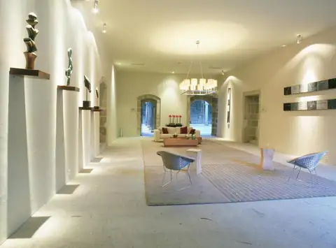 Salón amplio con paredes blancas, lámpara de araña y butacas de diseño en el Parador de Santo Estevo