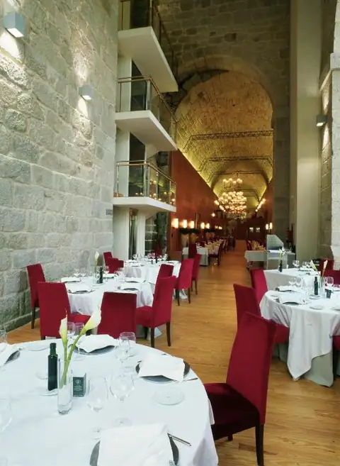 Restaurante con mesas vestidas y sillas rojas bajo una bóveda de piedra del Parador de Santo Estevo