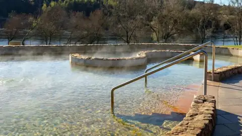 Vapor sobre el agua termal de una de las piscinas de Teáns, con el Miño al fondo