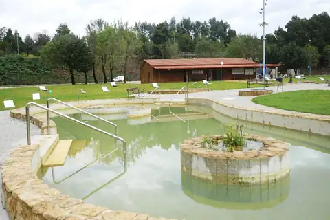 Piscina termal con escalera y barandillas junto a la zona verde y los vestuarios de Teáns