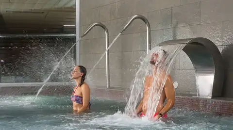 Pareja bajo los chorros y la cascada de la piscina del Hotel Thalasso Cantábrico Las Sirenas