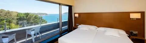 Habitación con cama doble y terraza con vistas al mar en el Hotel Thalasso Cantábrico Las Sirenas