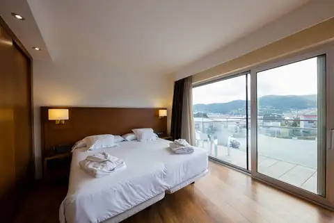Habitación con dos camas, albornoces y ventanal con terraza en el Hotel Las Sirenas de Viveiro